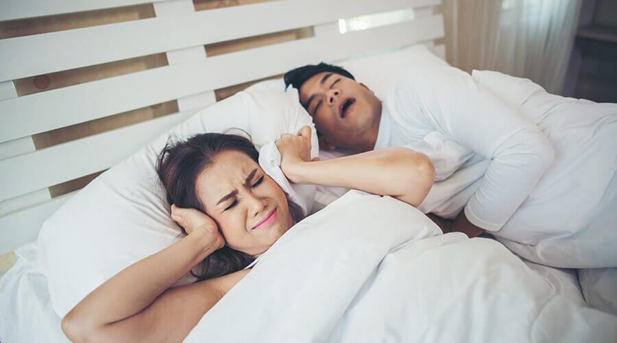A woman disturbed by his partner loud snoring. Consult primary care for sleep apnea with Side Health.