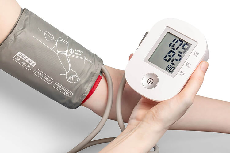 Person checking its high blood pressure using a digital high blood pressure monitor. Consult primary care for high blood with Side Health.